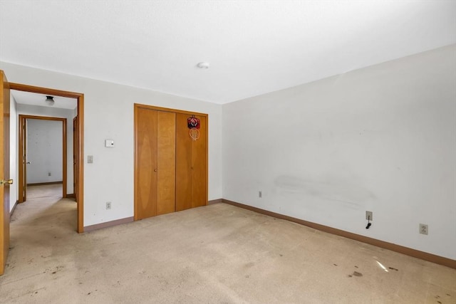 unfurnished bedroom featuring baseboards, a closet, and light colored carpet