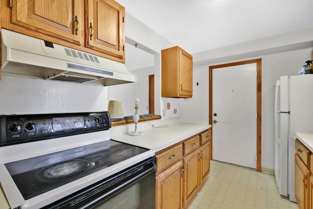 kitchen with under cabinet range hood, electric stove, light countertops, freestanding refrigerator, and light floors