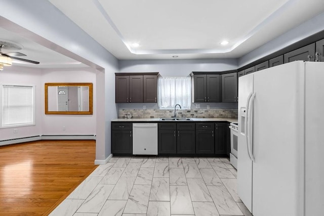 kitchen featuring white appliances, a raised ceiling, a sink, marble finish floor, and backsplash