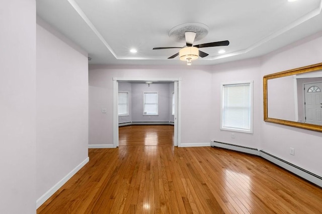 empty room featuring a baseboard radiator, baseboards, hardwood / wood-style floors, and recessed lighting