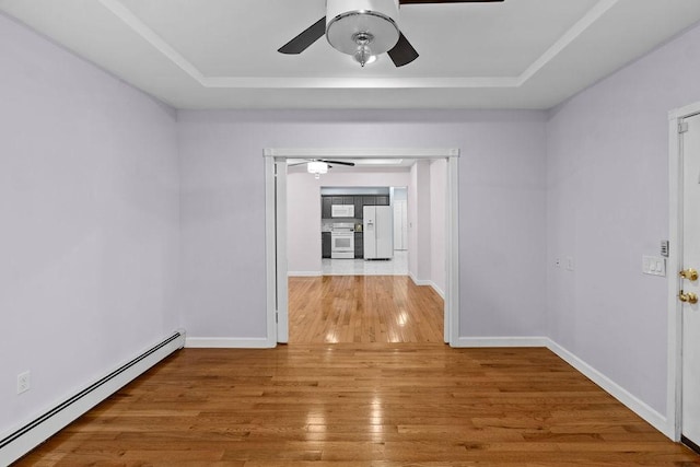 hallway with a baseboard heating unit, a tray ceiling, baseboards, and hardwood / wood-style floors