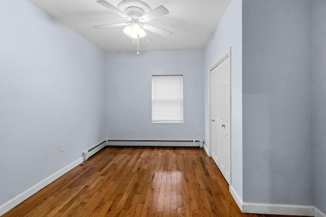 unfurnished bedroom with wood-type flooring, baseboards, baseboard heating, and a closet