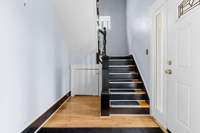 staircase featuring baseboards and wood finished floors