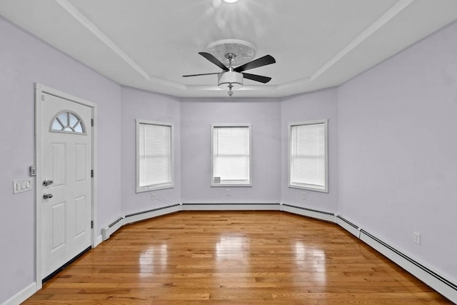 entrance foyer with baseboard heating, a raised ceiling, ceiling fan, and light wood finished floors