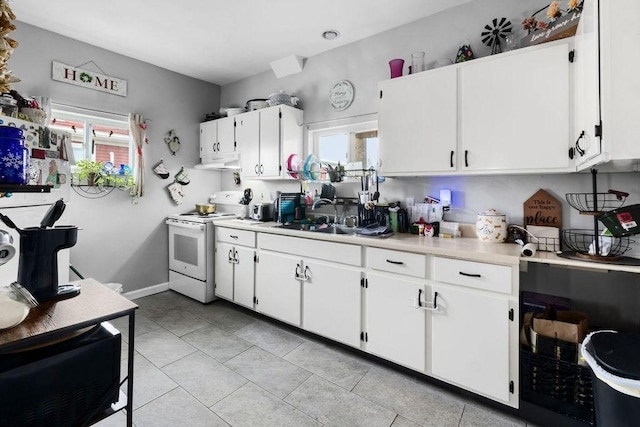 kitchen with a wealth of natural light, white electric stove, light countertops, and a sink