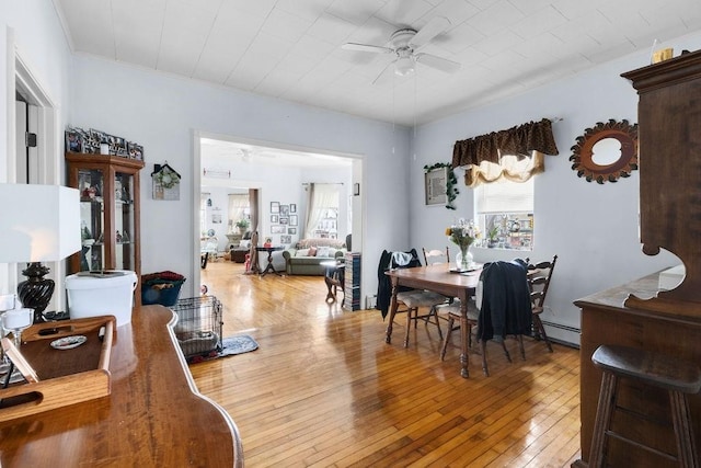 dining space featuring a baseboard radiator, wood-type flooring, and ceiling fan