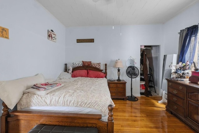 bedroom featuring ornamental molding, a baseboard radiator, and wood finished floors