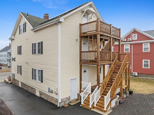 back of property featuring stairway, a chimney, and a wooden deck