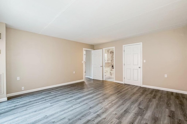 4975 Washington St Unit 313, Boston, MA 02132 - unfurnished bedroom featuring wood finished floors, baseboards, and ensuite bath
