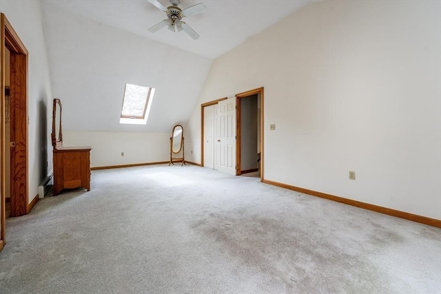 unfurnished bedroom with baseboards, vaulted ceiling with skylight, and light carpet