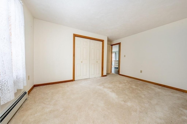unfurnished bedroom featuring baseboards, a baseboard heating unit, a closet, and light colored carpet