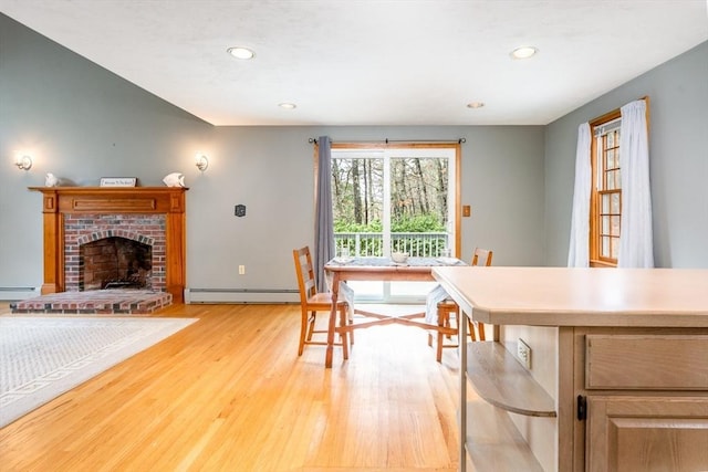 dining room featuring a fireplace, recessed lighting, baseboard heating, a baseboard heating unit, and light wood-type flooring