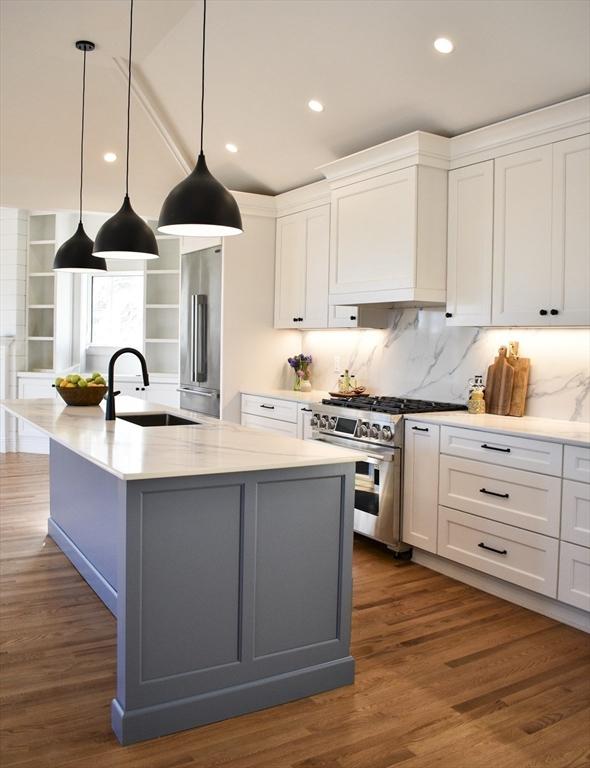 kitchen with white cabinetry, sink, high quality appliances, and a center island with sink