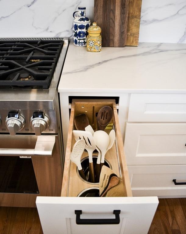 room details featuring white cabinets, backsplash, light stone countertops, dark wood-type flooring, and stainless steel range with gas stovetop