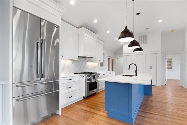 kitchen with sink, white cabinetry, pendant lighting, stainless steel appliances, and a kitchen island with sink