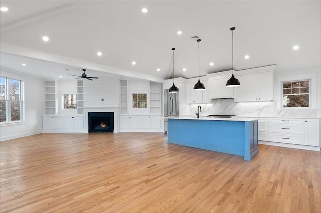 kitchen featuring white cabinetry, decorative light fixtures, plenty of natural light, and a center island with sink