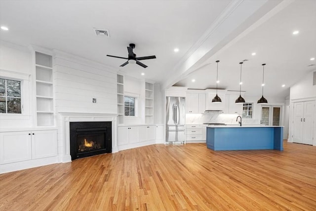 unfurnished living room with sink, crown molding, light hardwood / wood-style flooring, and ceiling fan