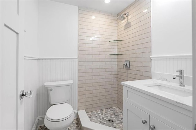 bathroom featuring vanity, toilet, and tiled shower