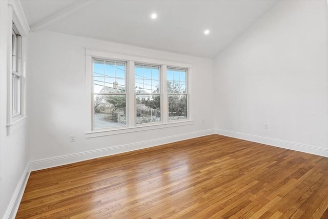 spare room featuring lofted ceiling and hardwood / wood-style floors