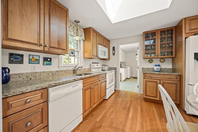 54 Mcnamara Ave, Yarmouth, MA 02673 - kitchen featuring white appliances, brown cabinetry, a sink, a skylight, and light wood finished floors