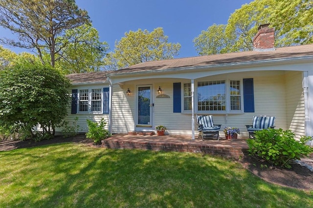 54 Mcnamara Ave, Yarmouth, MA 02673 - view of front of home featuring a front lawn, a chimney, and covered porch