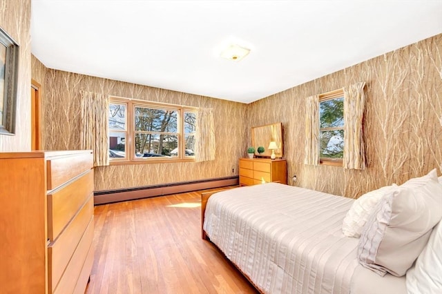 bedroom with a baseboard heating unit and wood finished floors