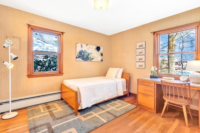 bedroom featuring baseboard heating, wood finished floors, and wallpapered walls