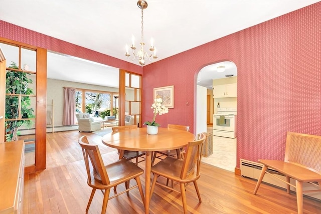 dining room with wallpapered walls, light wood-style flooring, arched walkways, and a baseboard heating unit