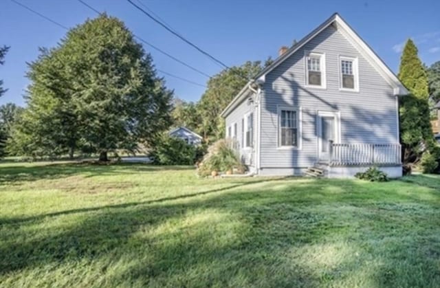 back of house featuring a lawn and a chimney