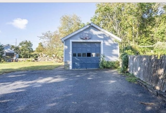 detached garage featuring driveway and fence