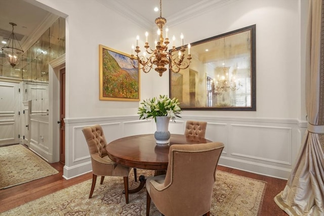 dining area featuring an inviting chandelier, wood finished floors, ornamental molding, and a decorative wall