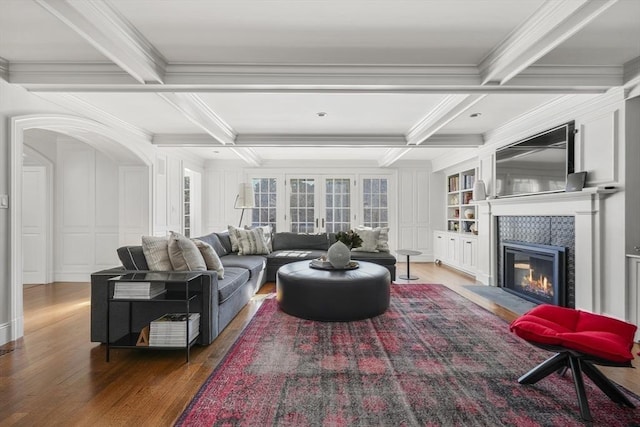 living room with a tile fireplace, coffered ceiling, and beam ceiling