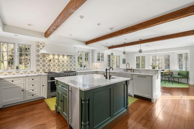 kitchen featuring pendant lighting, stainless steel range, dark hardwood / wood-style floors, and a kitchen island with sink