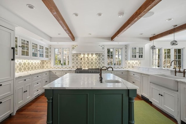 kitchen with light stone counters, sink, and a kitchen island with sink