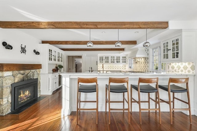 kitchen featuring dark hardwood / wood-style flooring, decorative light fixtures, a breakfast bar, and white cabinets