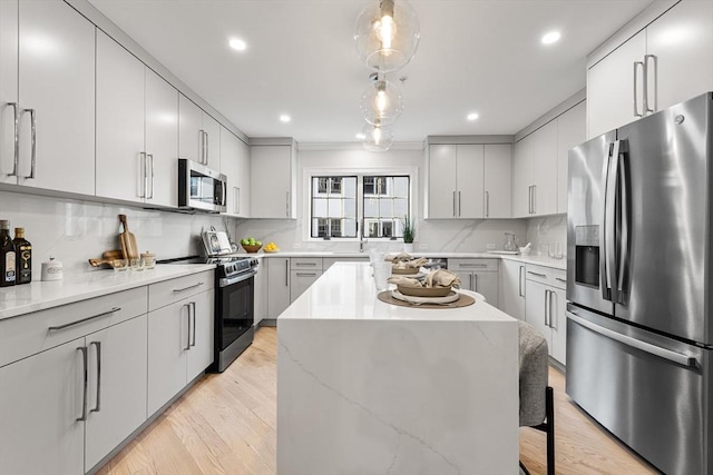 kitchen featuring pendant lighting, light hardwood / wood-style flooring, stainless steel appliances, a kitchen island, and decorative backsplash