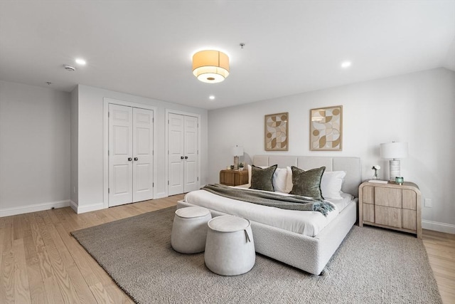 bedroom featuring multiple closets and light hardwood / wood-style flooring