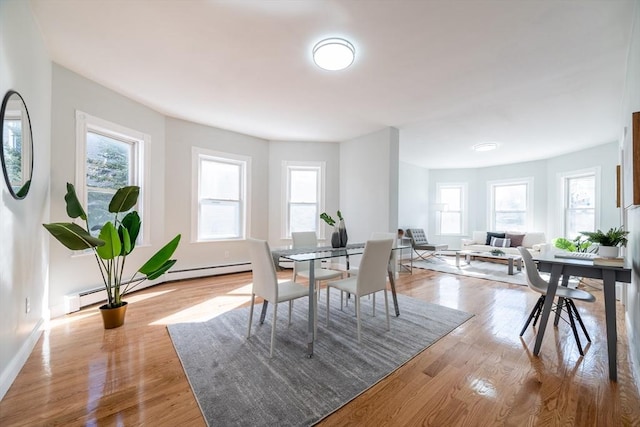 dining room with a baseboard radiator, light wood-style flooring, and baseboards