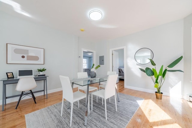 dining space with electric panel, baseboards, and wood finished floors