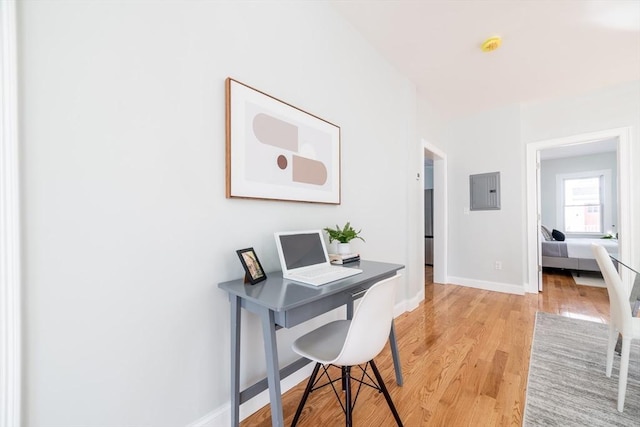 home office with baseboards, electric panel, and light wood-style floors