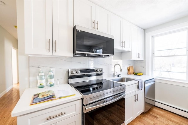 kitchen featuring a baseboard heating unit, stainless steel appliances, a sink, and light countertops