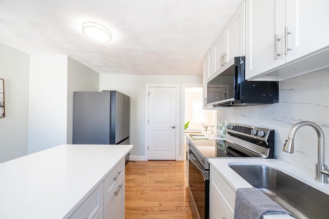 kitchen featuring light wood finished floors, white cabinetry, stainless steel appliances, and a sink