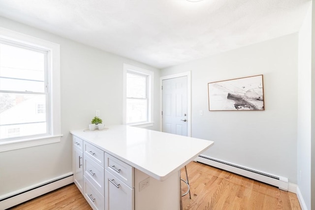 kitchen featuring a peninsula, a baseboard radiator, and a healthy amount of sunlight