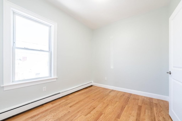 empty room featuring light wood-style floors, a baseboard radiator, and baseboards