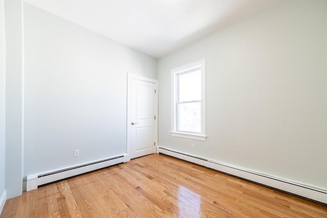 empty room with light wood-style floors and a baseboard heating unit