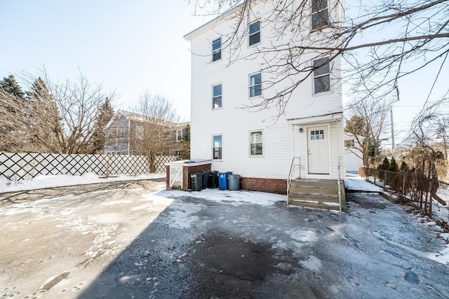 snow covered rear of property with fence