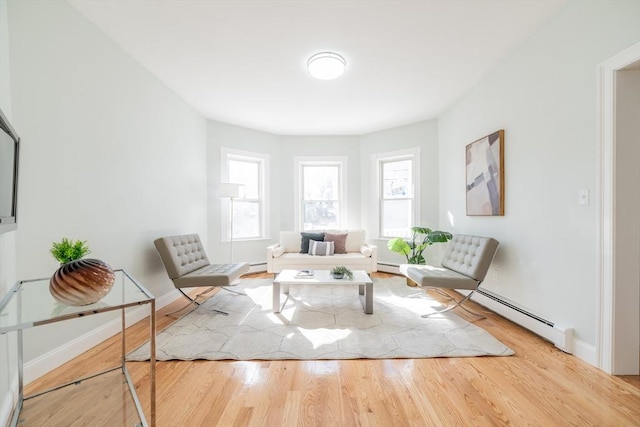 sitting room with baseboards, baseboard heating, and wood finished floors