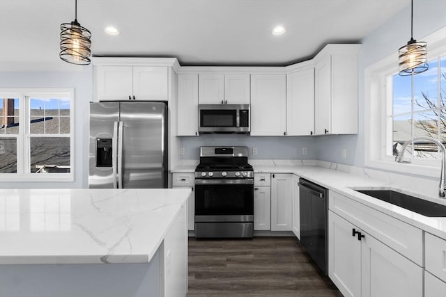 kitchen with appliances with stainless steel finishes, decorative light fixtures, sink, and white cabinets