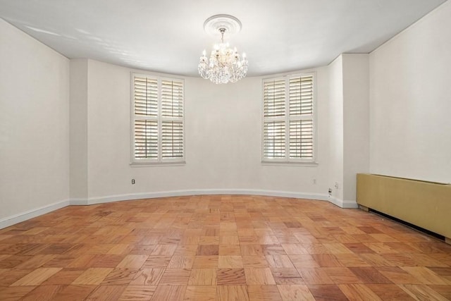 spare room featuring a notable chandelier and baseboards