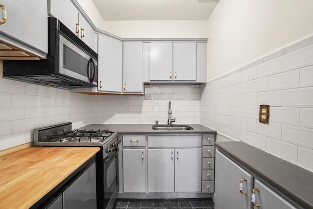 kitchen with black range with gas cooktop, a sink, wood counters, and decorative backsplash